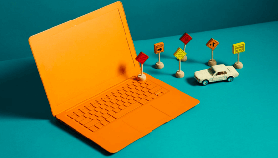 Un coche de juguete dirigiéndose hacia una computadora portátil